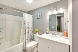 Un baño con ducha, inodoro, lavabo y espejo.