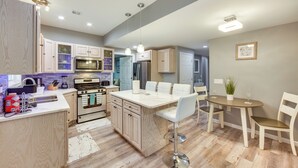 A modern kitchen with an island, bar stools, and a dining table with chairs.