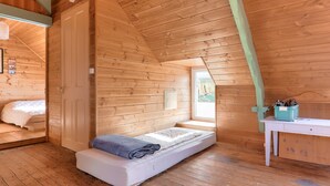 Accogliente camera in legno con letto a soppalco, una piccola scrivania e una finestra che fa entrare luce naturale.