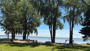 Ett grönområde med träd, en bänk och utsikt över en sjö.