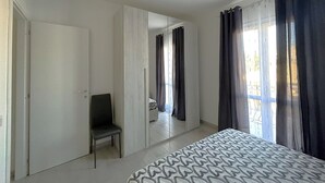 A bedroom with a bed, a chair, a wardrobe, and a mirror. - Affittimoderni La Maddalena - MADA19 (La Maddalena)