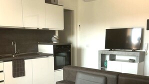 A modern kitchen with a dining area, a flat-screen TV, and a sofa. - Affittimoderni La Maddalena - MADA19 (La Maddalena)