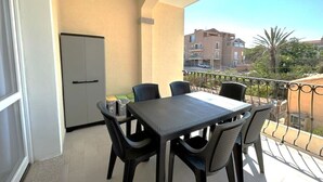 A balcony with a table and chairs, a refrigerator, and a view of buildings and trees. - Affittimoderni La Maddalena - MADA19 (La Maddalena)