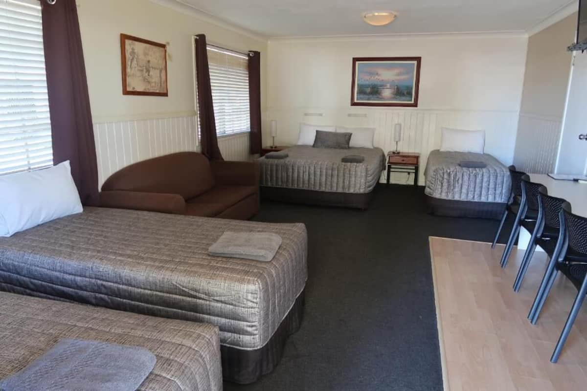 A hotel room with two beds, a sofa, a desk, and a chair.