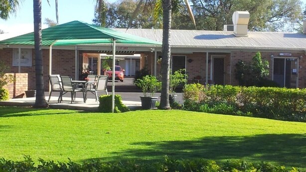 Ein Gebäude mit Gründach, einer überdachten Terrasse mit Sitzgelegenheiten und einem geparkten Auto davor.