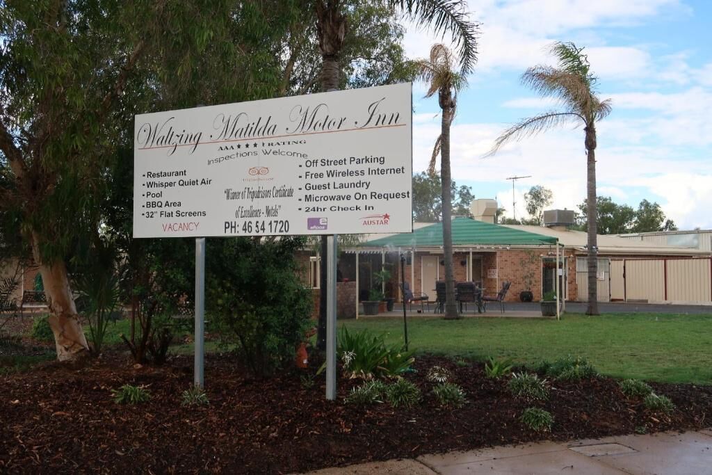 A sign for the Waltzing Motor Inn, listing amenities like a restaurant, pool, BBQ area, and 32" flat screens.
