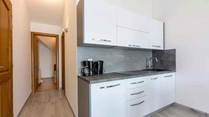 A modern kitchen with white cabinets, a grey countertop, and a stainless steel sink.