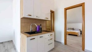 Eine moderne Küche mit Holzarbeitsplatte, Spüle und Schränken. Ein Bett ist durch einen offenen Durchgang in einem angrenzenden Raum sichtbar.