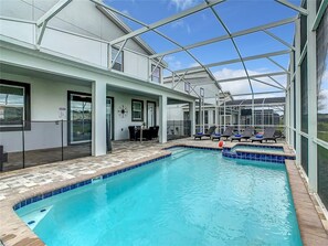 A pool area with lounge chairs and a covered patio. - Waterpark Enclave with Epic Game Room! Prvt Movie Theatre! Themed Luxury! (Davenport)
