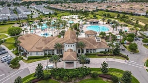 A large resort with multiple swimming pools, a central building with a tower, and a well-maintained landscape. - Waterpark Enclave with Epic Game Room! Prvt Movie Theatre! Themed Luxury! (Davenport)