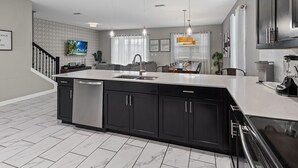 A modern kitchen with a large island, black cabinets, and stainless steel appliances. - Waterpark Enclave with Epic Game Room! Prvt Movie Theatre! Themed Luxury! (Davenport)