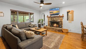 A living room with a sofa, coffee table, fireplace, and a TV mounted on the wall.