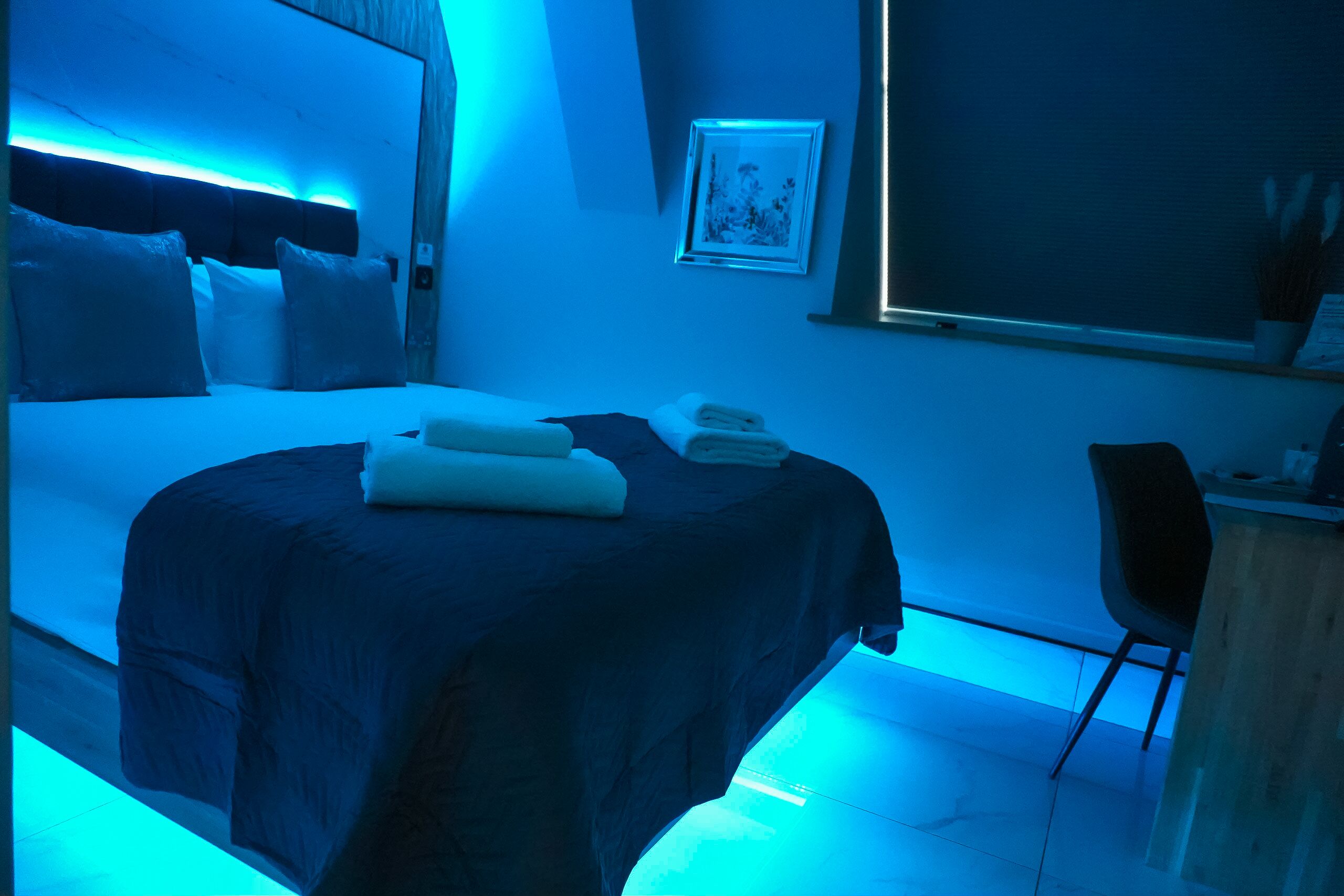 A bedroom with a bed, pillows, a bedside table, and a window.