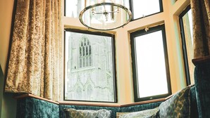 A corner seating area with a view of a cathedral through a large window. - The Arundell Hotel (Boston)