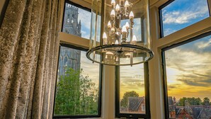A room with large windows, a chandelier, and a view of a building and trees. - The Arundell Hotel (Boston)