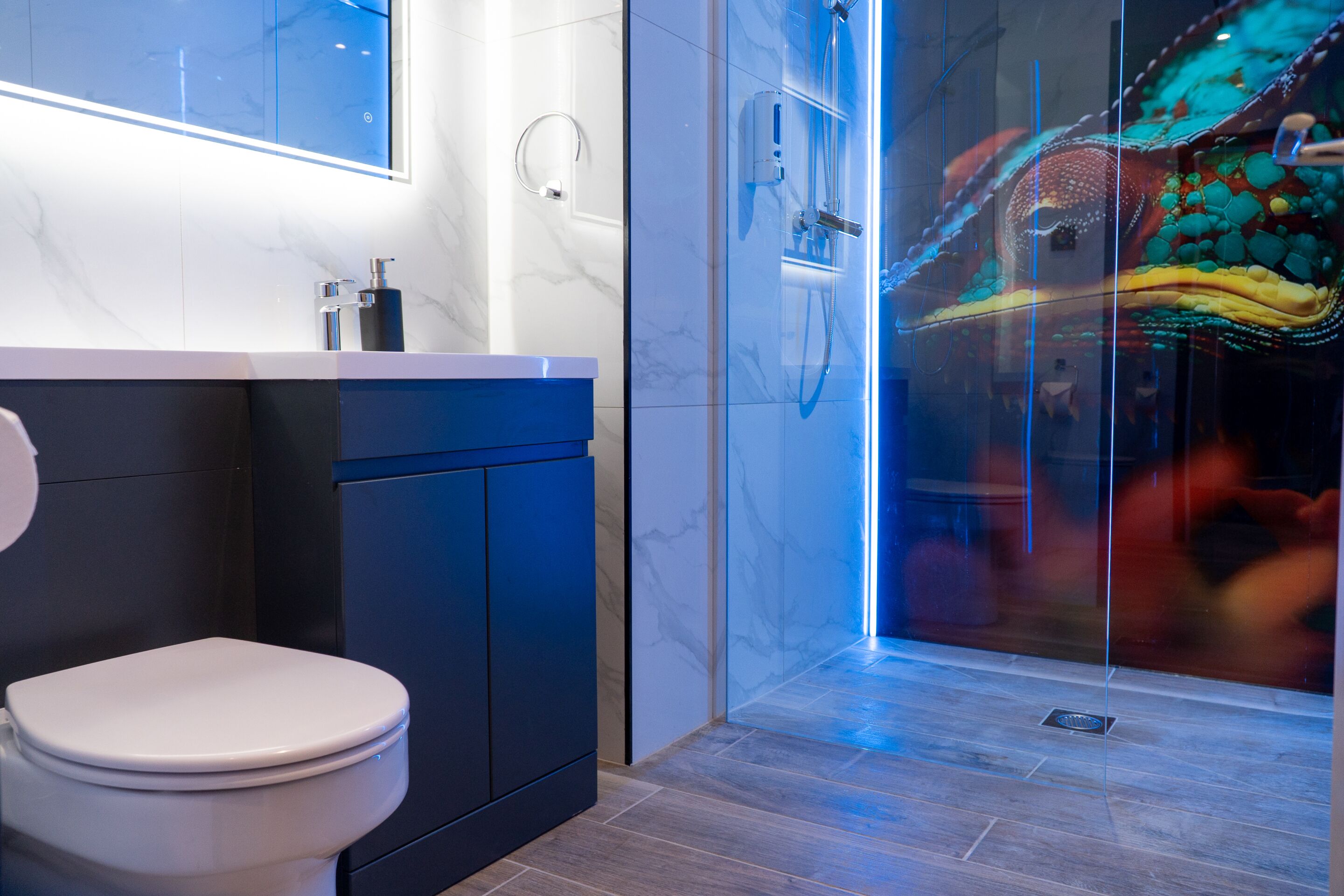 Un baño moderno con inodoro, lavamanos y cabina de ducha con mampara de vidrio.