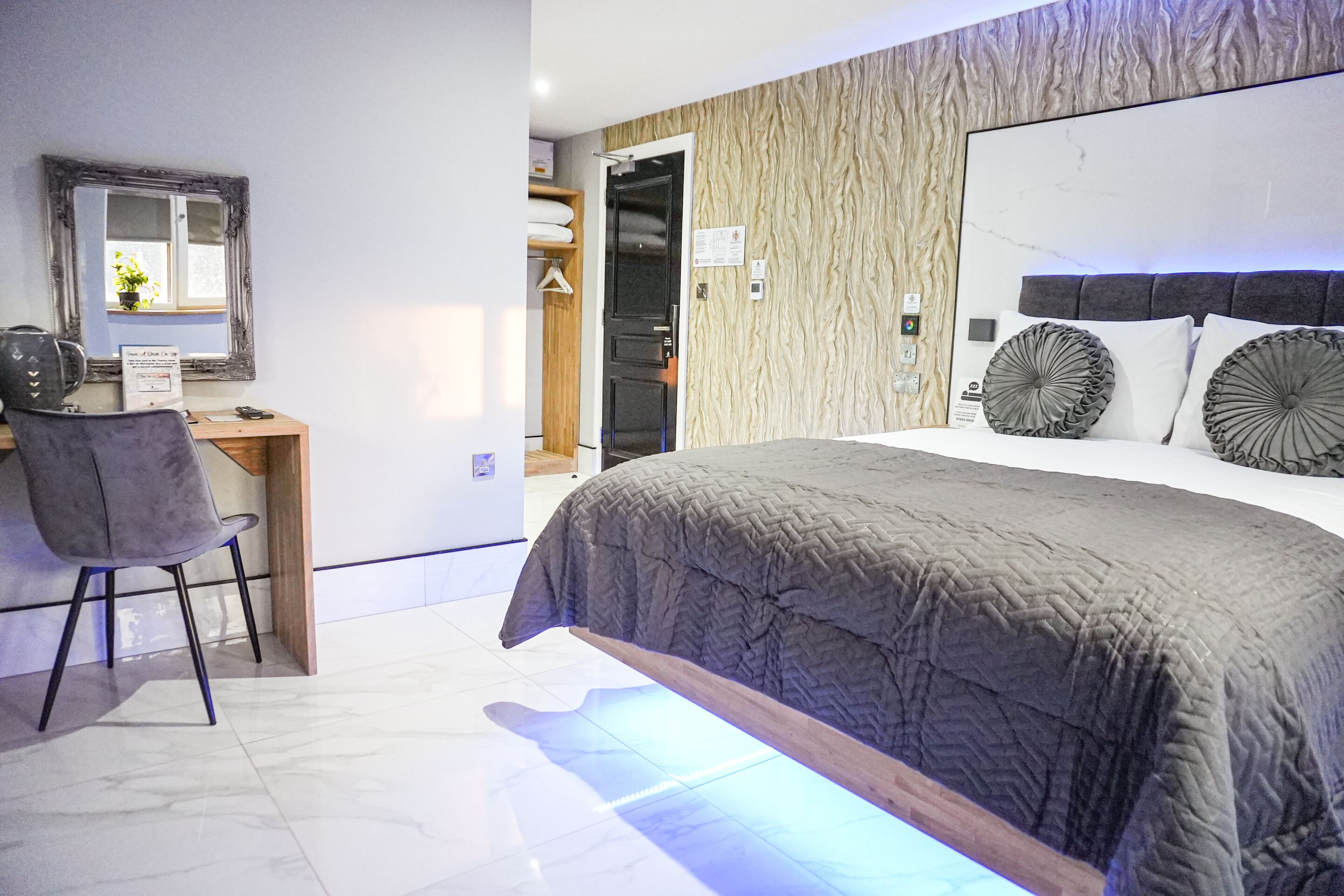 A modern bedroom with a large bed, a desk, and a chair.
