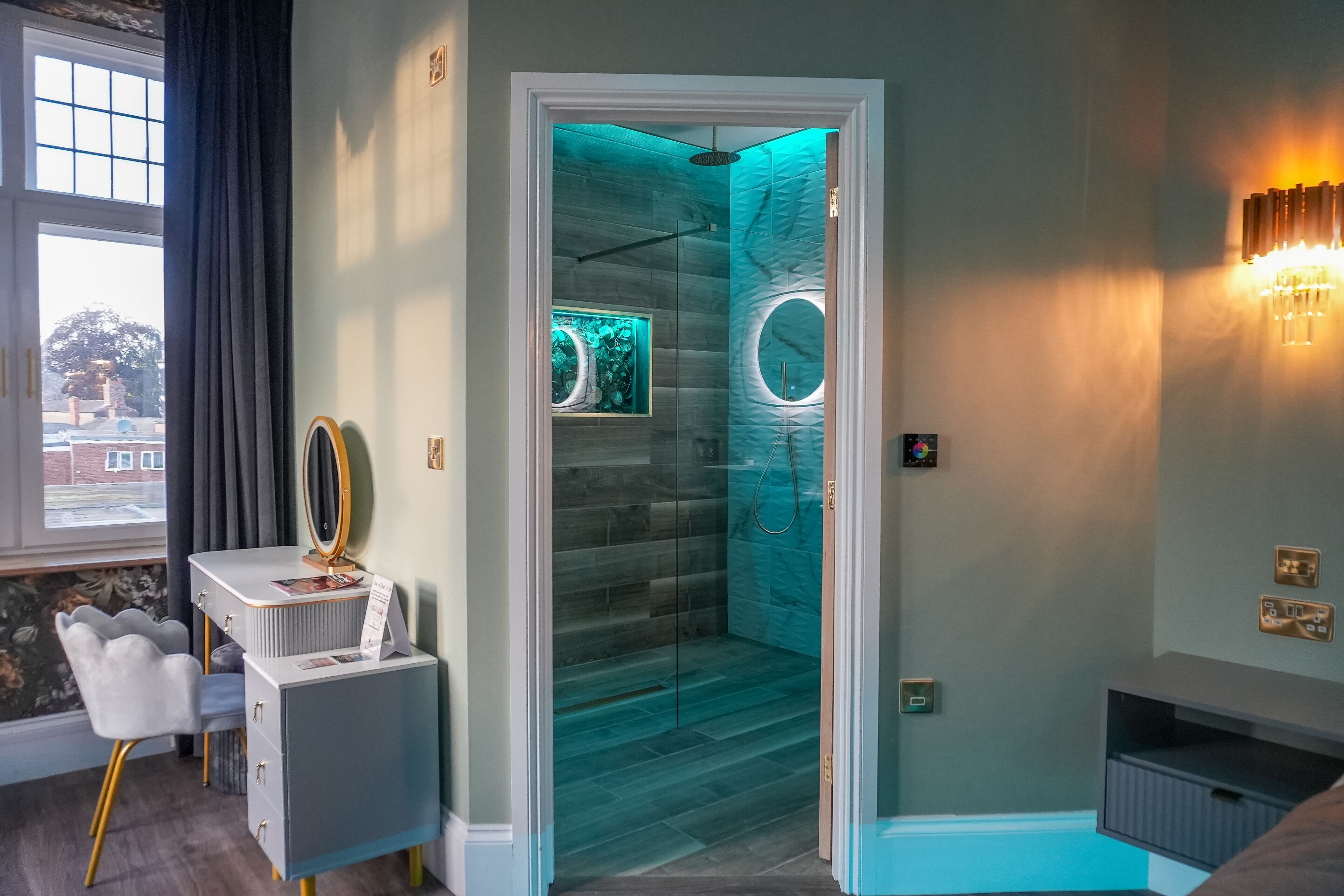 A modern bathroom with a glass-enclosed shower, a vanity with a mirror, and a decorative wall light.
