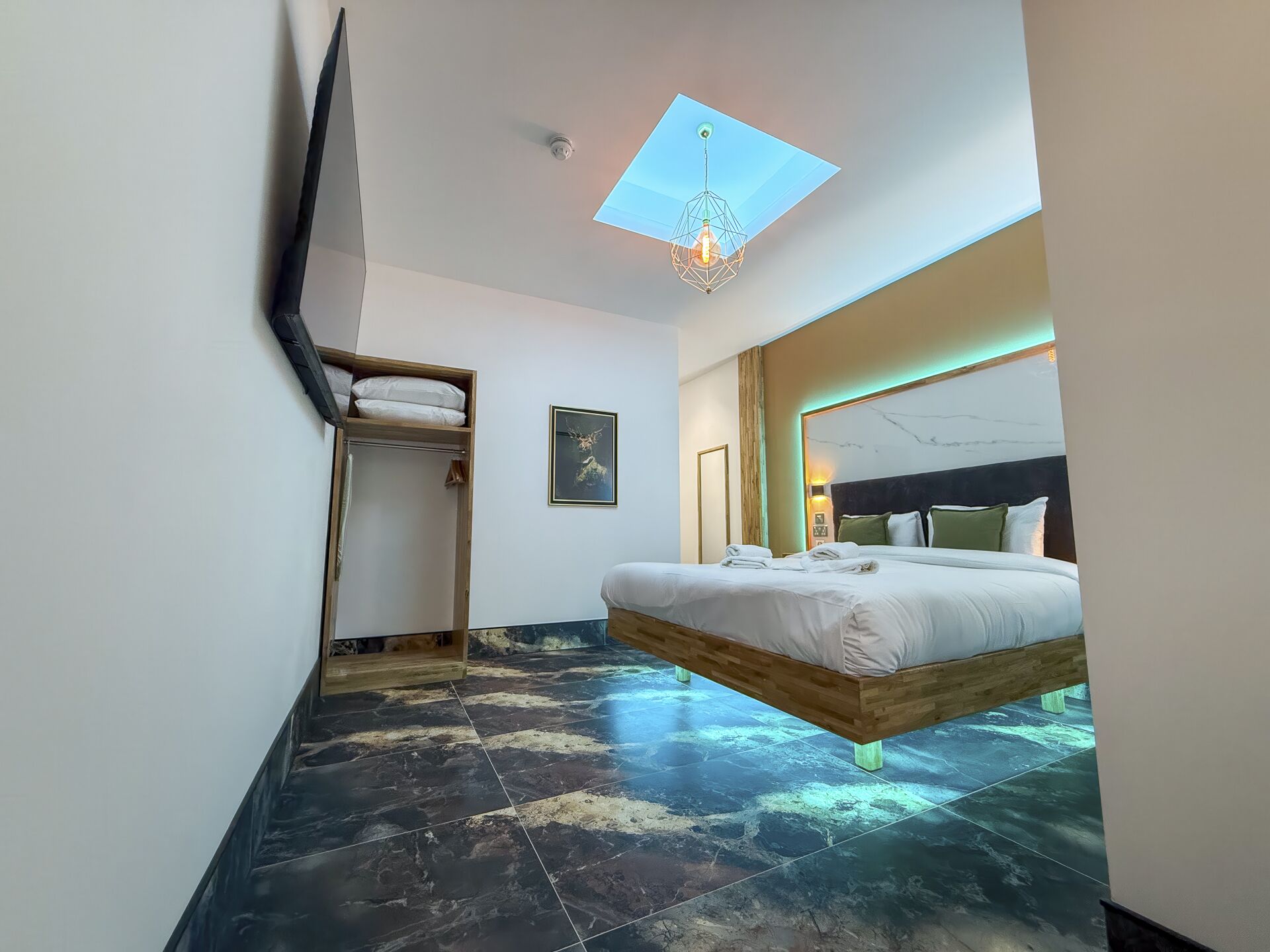 Un dormitorio moderno con una cama suspendida del techo, un tragaluz y un espejo grande.