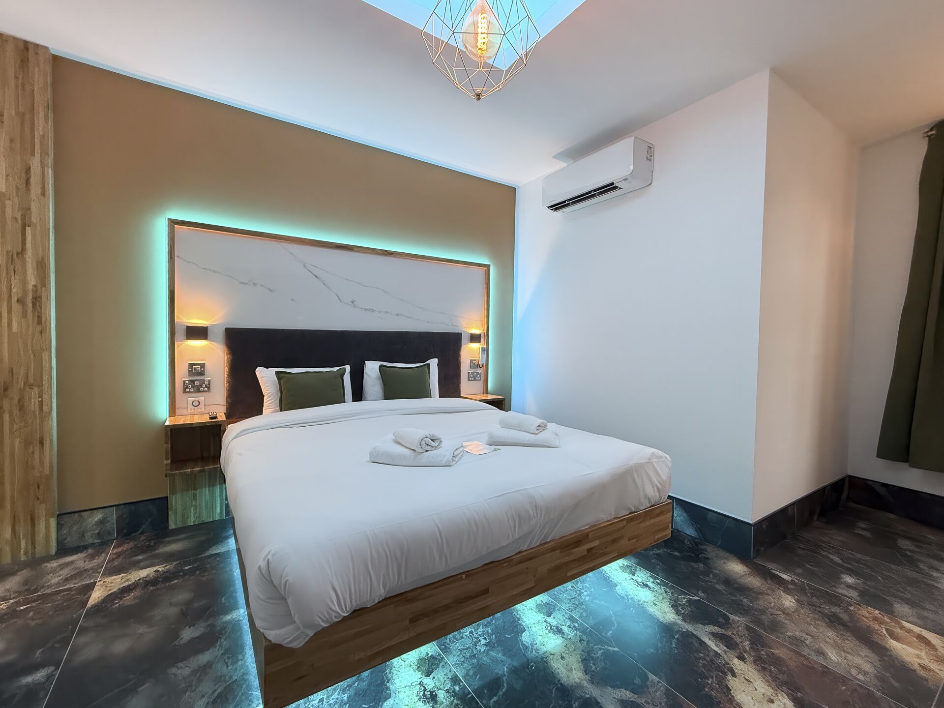 A modern hotel room with a suspended bed, a marble headboard, ambient lighting, and an air conditioning unit.