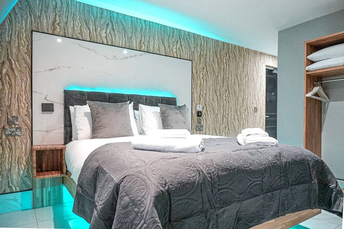 A modern bedroom with a marble headboard, a glass floor, and a wooden wardrobe.