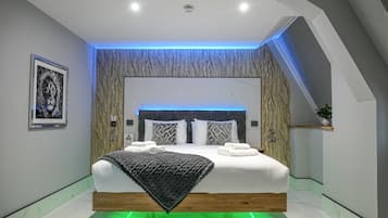 Un dormitorio moderno con cama, cabecera, una obra de arte en la pared y una lámpara en el techo.