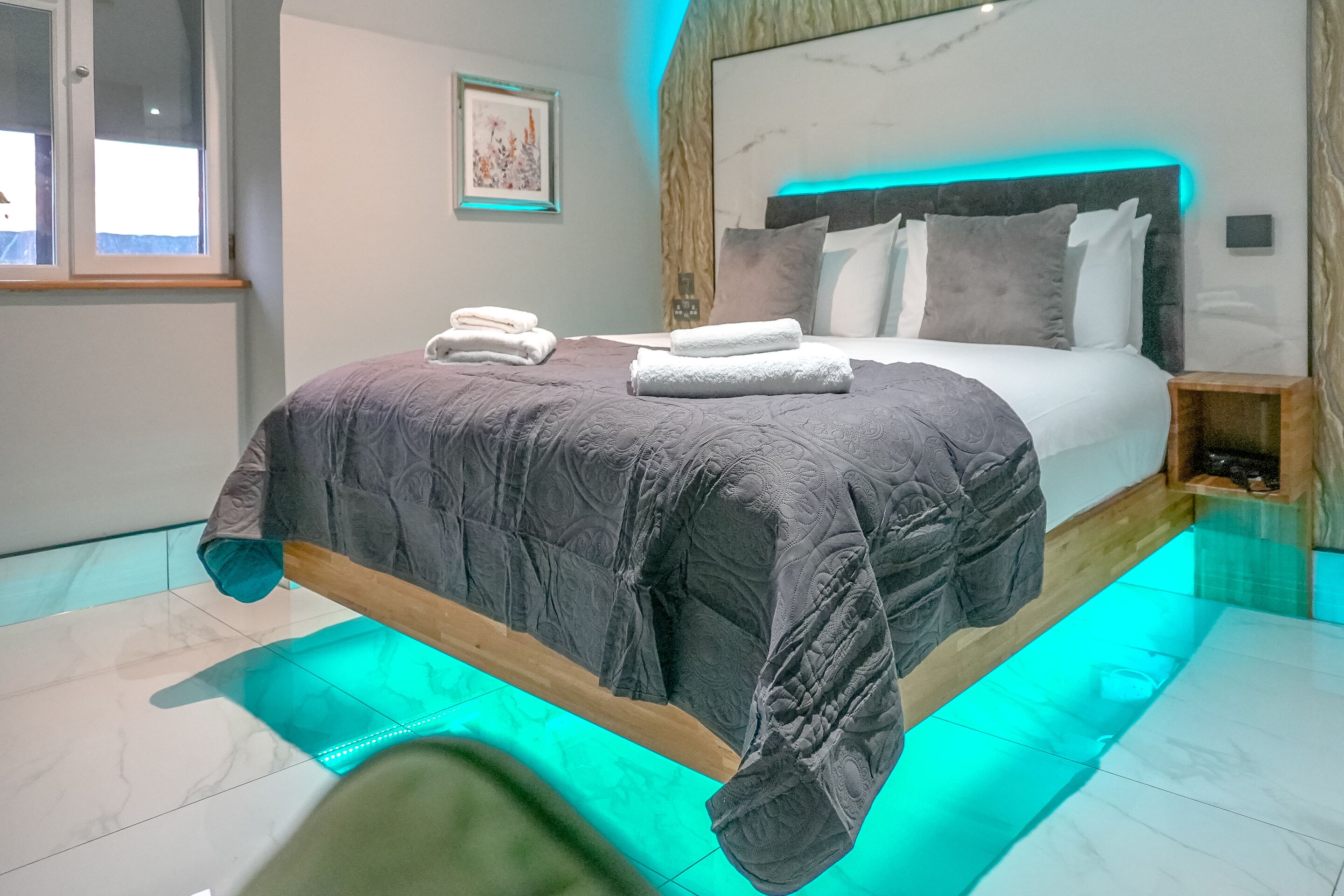 A modern bedroom with a bed, bedside tables, and a window.
