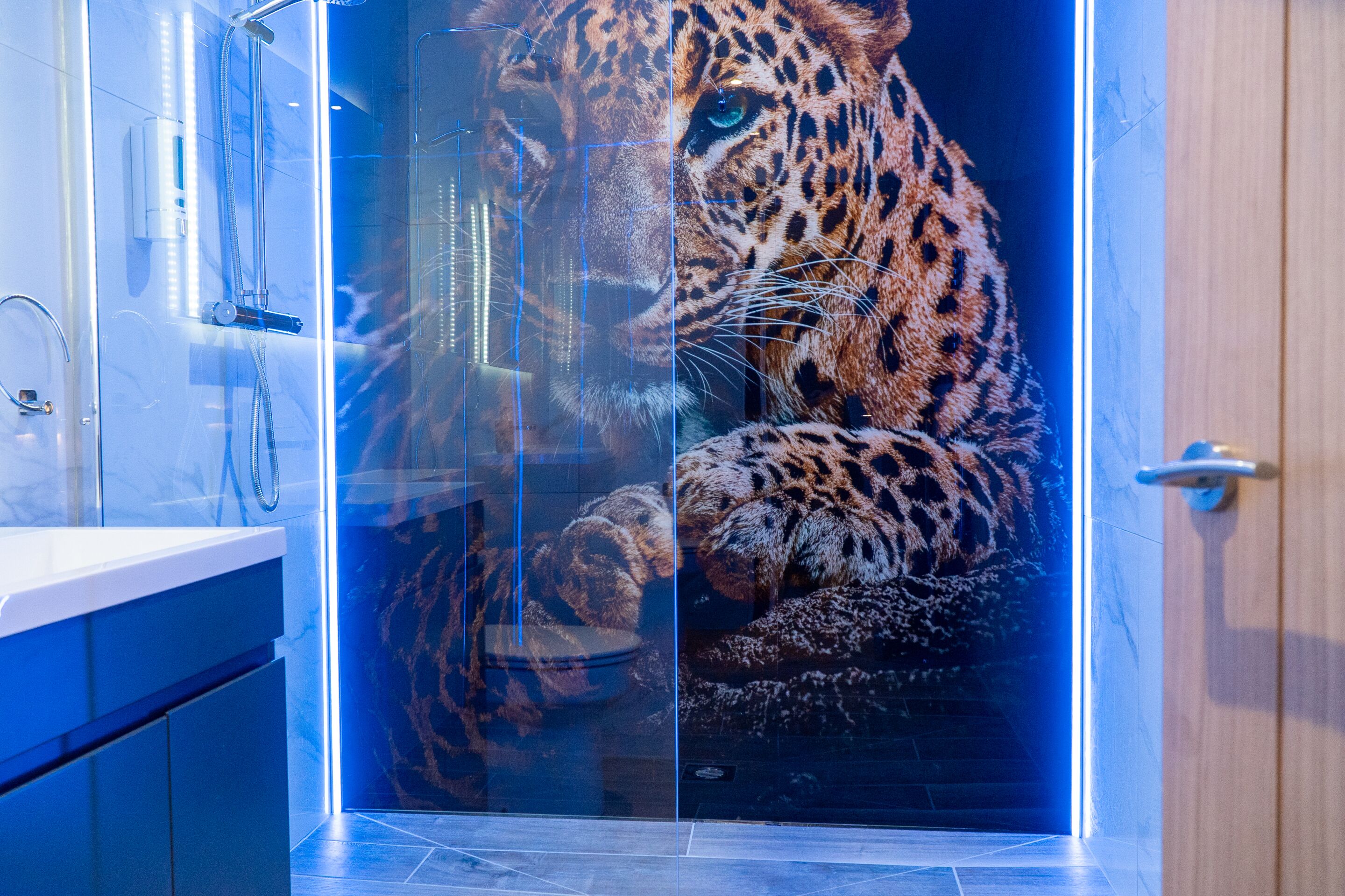 A bathroom with a glass enclosure featuring a leopard.