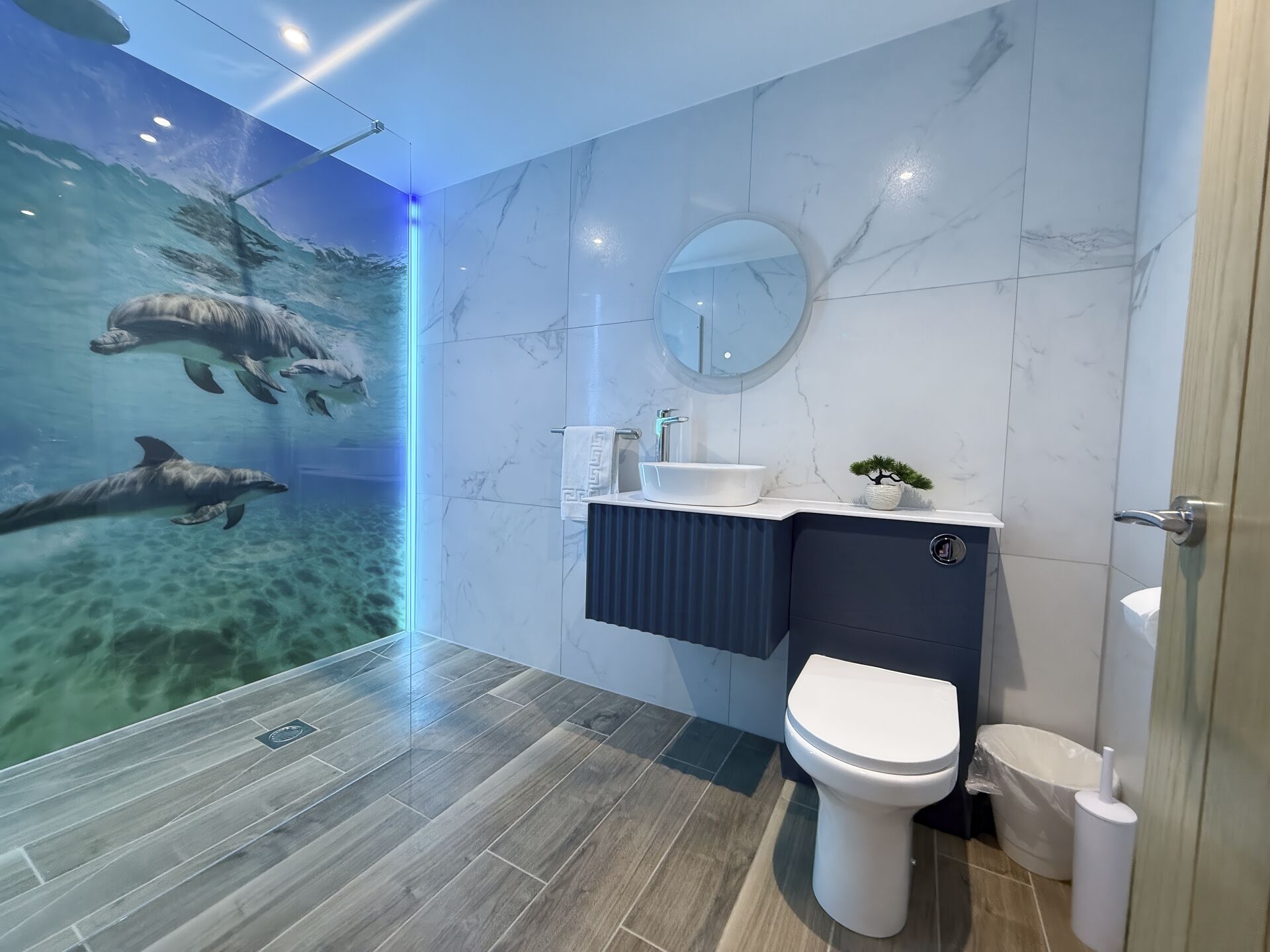 A modern bathroom with a large mirror, a sink, and a toilet.