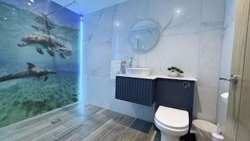 A modern bathroom with a large mirror, a sink, and a toilet.