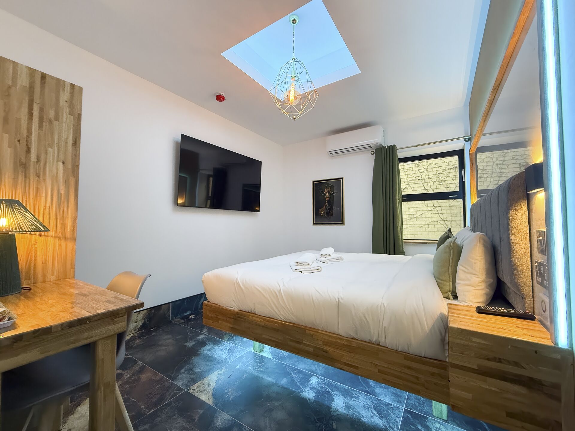 Een moderne hotelkamer met een bed, een bureau, een televisie en een dakraam.