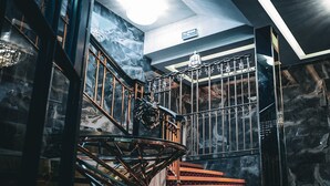 A grand staircase with a metal railing and a stone wall backdrop. - The Arundell Hotel (Boston)