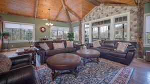 A spacious living room with leather sofas, a large rug, and a stone accent wall. - Enjoy your Private 4 Acres @ Owl Creek - Hot Tub, Fire Pit (Galena)