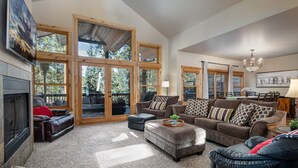 A spacious living room with large windows, a fireplace, and a dining area with a chandelier.