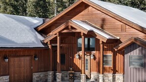 A wooden cabin with a stone foundation, a large garage door, and a welcoming sign.