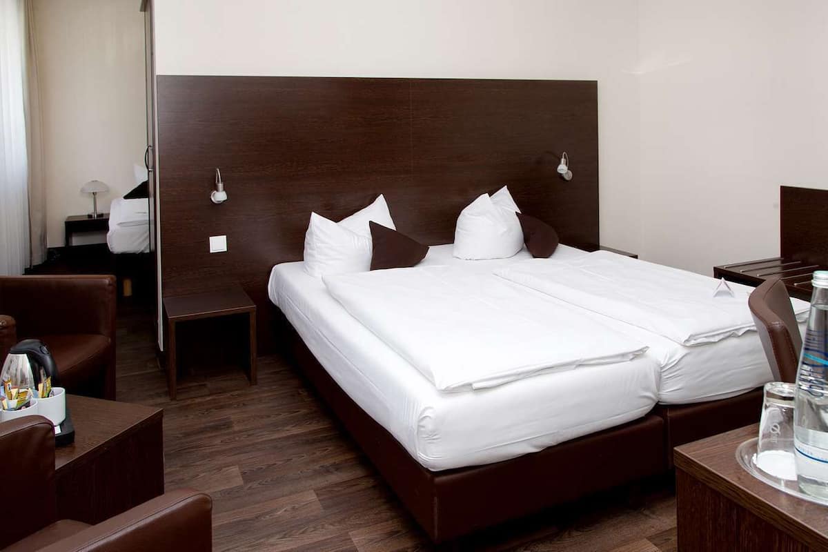 A hotel room with a large bed, two bedside tables, a desk, and a chair.