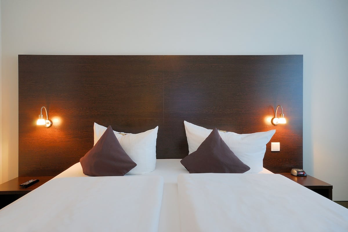 A hotel room with a large bed, two bedside tables, and wall-mounted lighting.