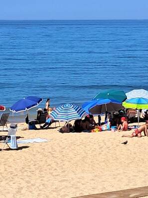 A beach with multiple umbrellas and beach chairs.