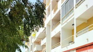 A street with outdoor seating at a restaurant, a multi-story building with balconies, and a clear sky. - T2 Requinte A C e Vista Mar Wifi Garagem (Loulé)