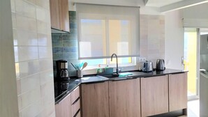 A modern kitchen with a central island, wooden cabinets, and a large window providing natural light. - T2 Requinte A C e Vista Mar Wifi Garagem (Loulé)