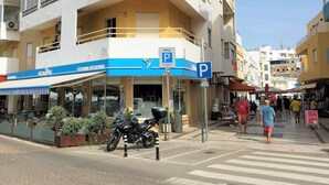 A multi-story building with balconies, a visible parking sign, and a motorcycle parked in front. - T2 Requinte A C e Vista Mar Wifi Garagem (Loulé)