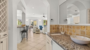 Une cuisine moderne dotée d’un grand îlot central, d’un évier à deux bacs et d’un ventilateur de plafond.