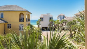 Un quartier résidentiel en bord de mer, avec un bâtiment jaune, une structure moderne blanche et une vue sur la plage.