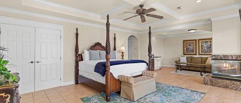 A spacious bedroom with a four-poster bed, a sitting area with a sofa, and a fireplace.