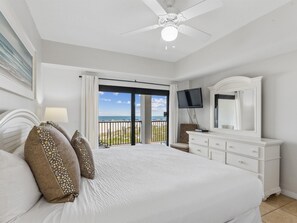 Ein Hotelzimmer mit Bett, Fernseher, Kommode und einem Balkon mit Meerblick.