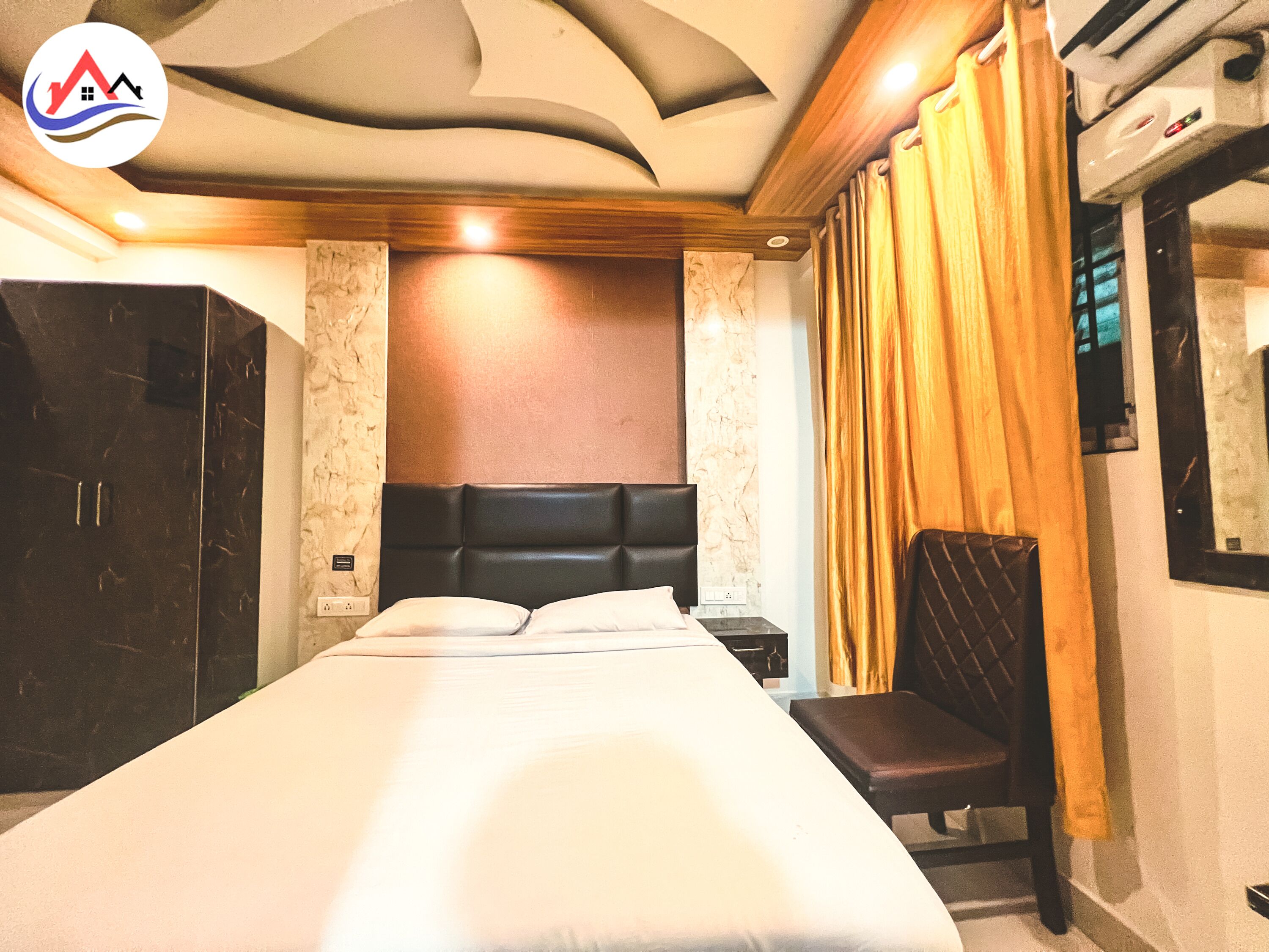 A hotel room with a large bed, a wooden headboard, a seating area, and a minibar.
