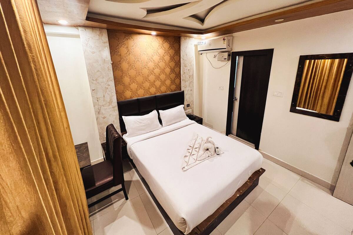A hotel room with a bed, a chair, a wardrobe, and a bathroom door.