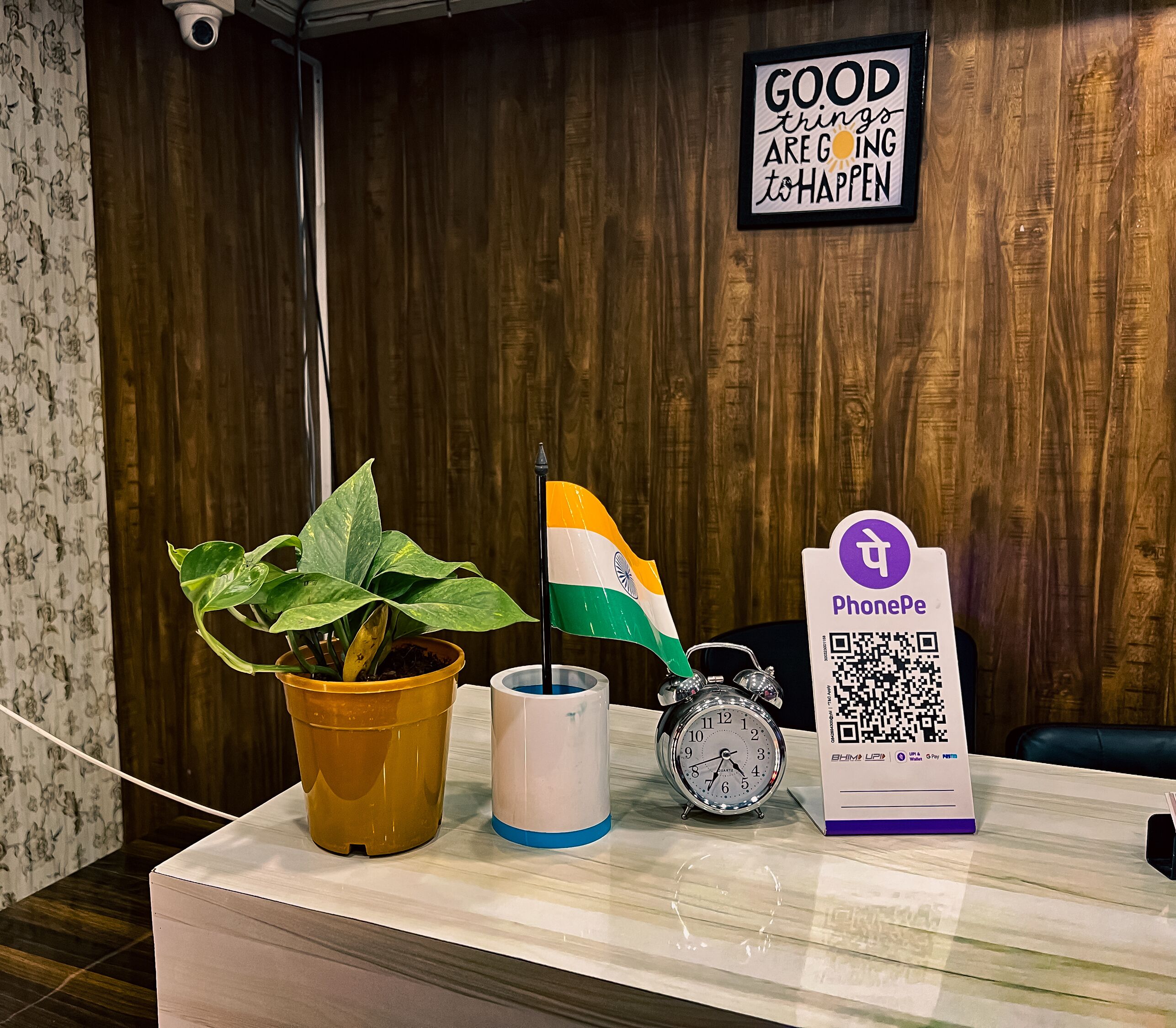 A reception desk with a potted plant, a flag, a clock, and a PhonePe sign.