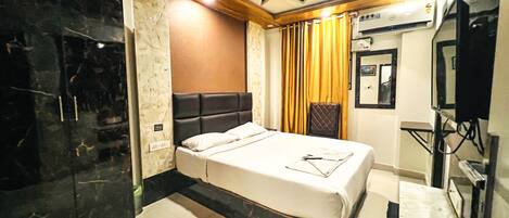 A hotel room with a bed, a television, and a minibar.