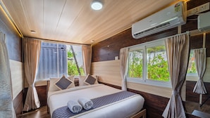 A neatly arranged bedroom with a bed, curtains, and an air conditioning unit.